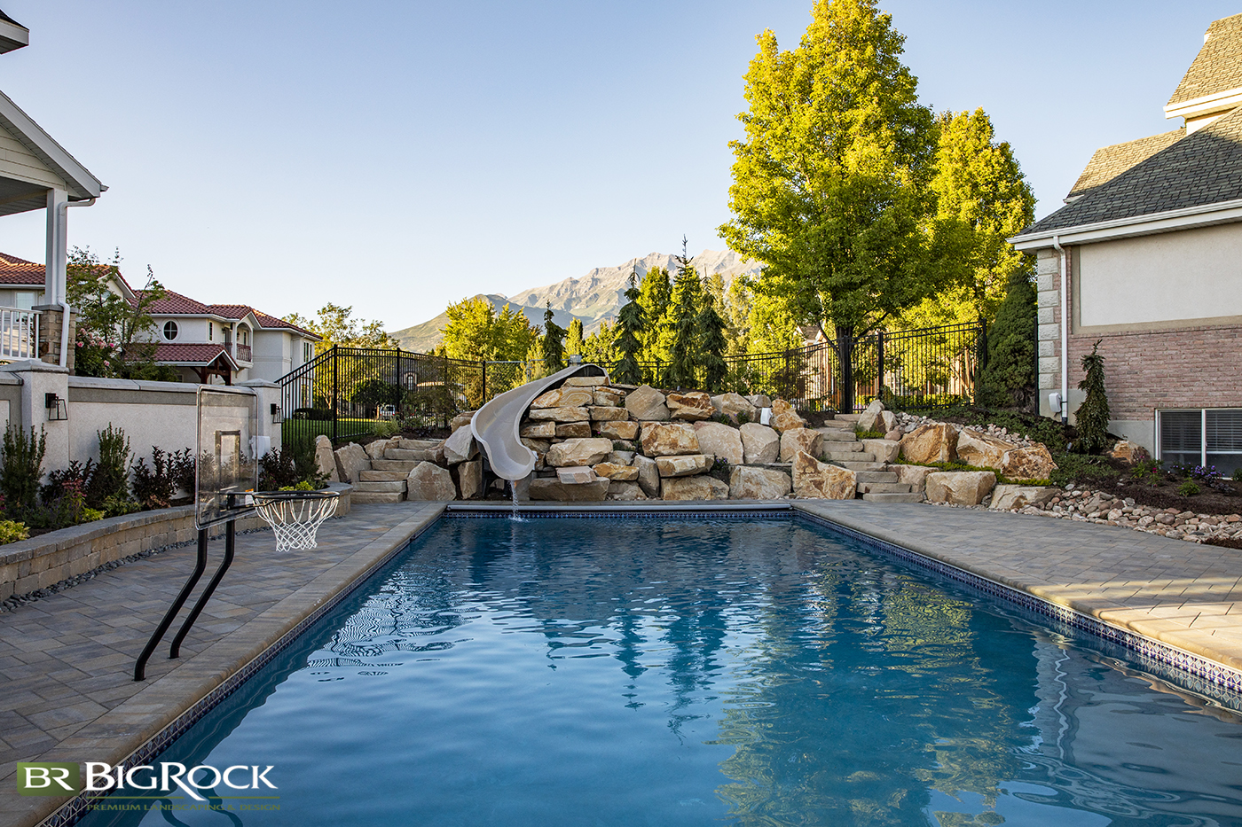 Step up your pool design and installation with a pool slide surrounded by natural rock for the ultimate backyard pool design.