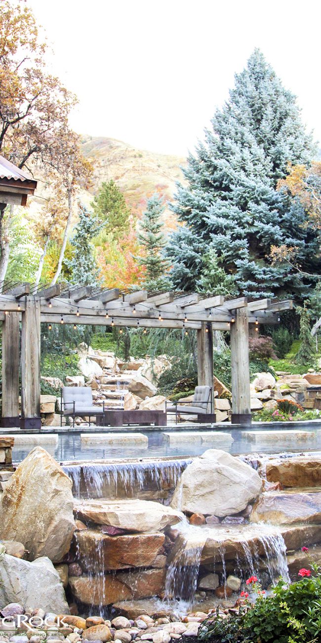Create a lush and natural backyard landscape with natural stone waterfalls and stone stairways.