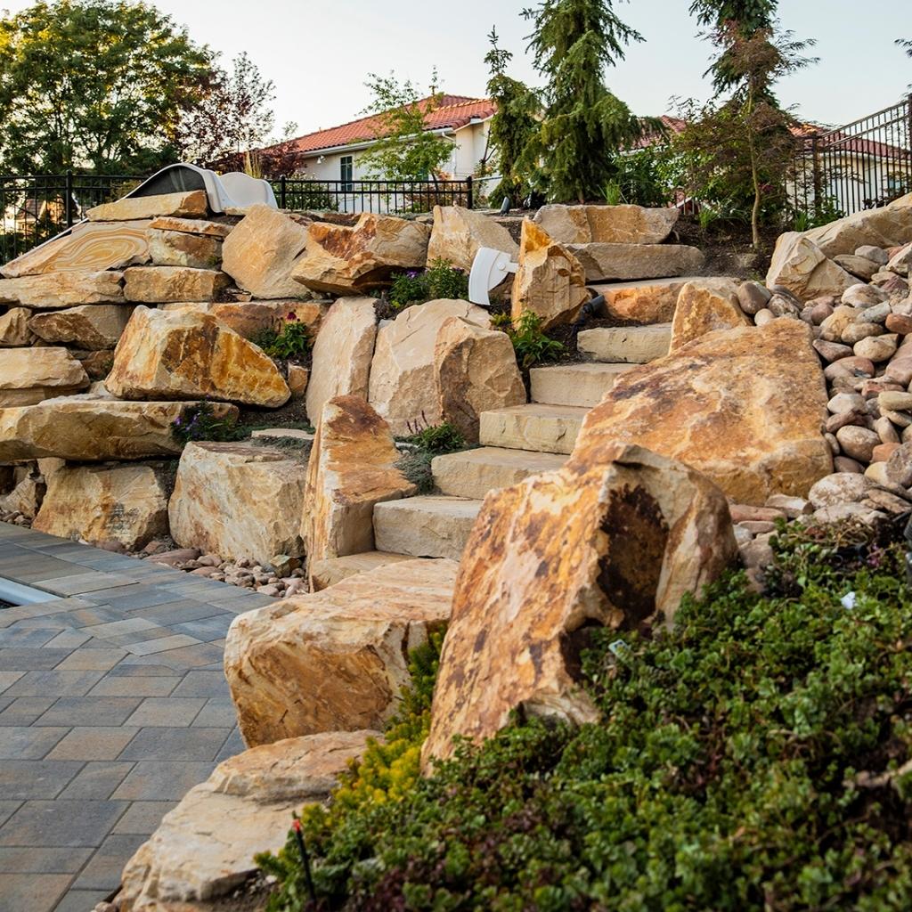 Designing, let alone installing, a rock wall feature in your yard is no small feat- between planning, excavating, digging, leveling, and then finally laying the rock, it’s a job most homeowners shouldn’t tackle alone
