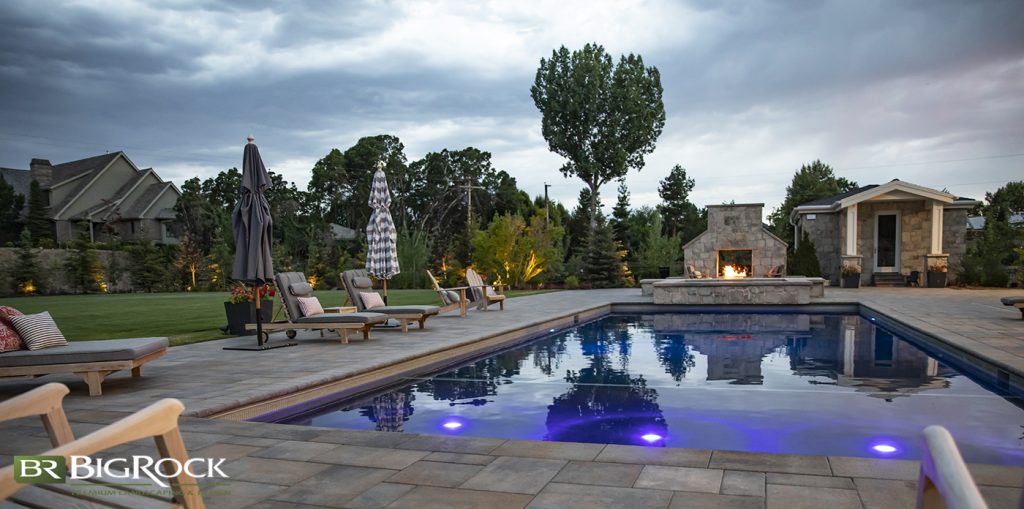 Built with natural stone, both the pool decking and the fireplace create a focal point for this landscaping design