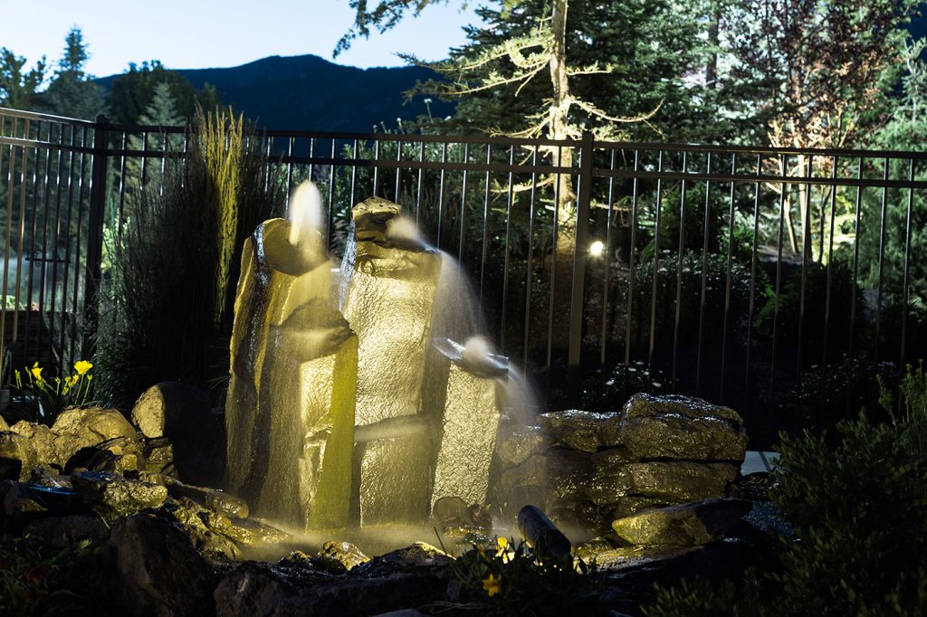 water feature with cement sculpture and outdoor lighting