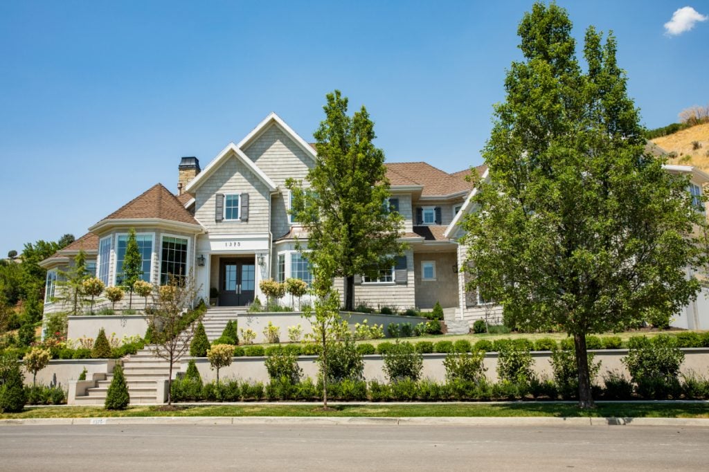 The use of retaining walls, a large pathway to the front door, and a variety of layered greenery creates a visually appealing look that guides your eye around the yard and up to the home’s entrance.