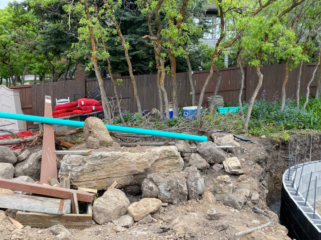 here is the before or perhaps more accurately and “in progress” shot from one of our backyard remodel projects. Notice the curve of the retaining wall in the lower right corner of the photo and the large boulder?