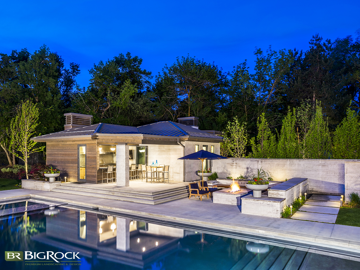 An outdoor living area with a modern look and feel, including the pool and landscaping with cement stairs.