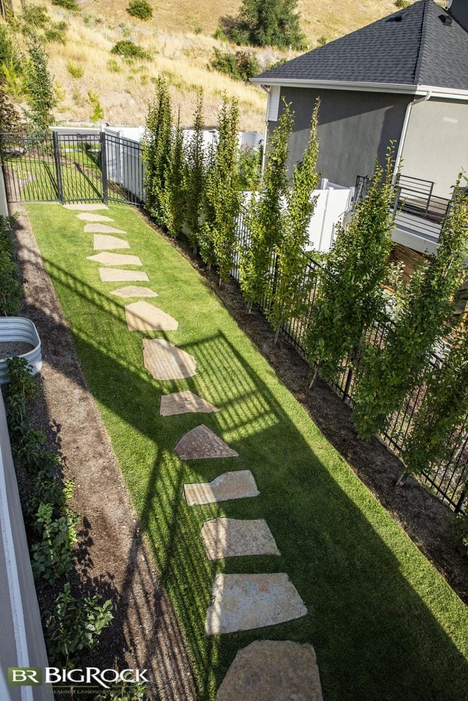 Natural stone pavers line the side yard to create a natural look in the grass. However, you will still have to maintain the grass around and between the pavers.