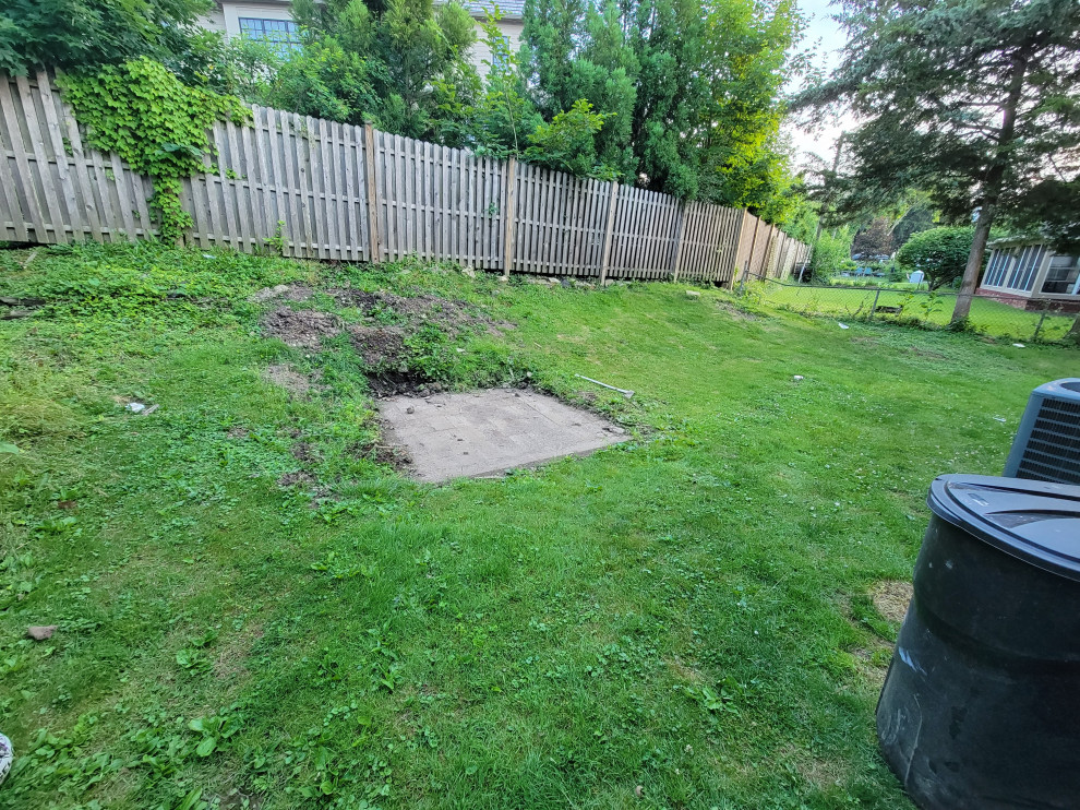 Existing concrete masonry patio previously covered by a shed. The existing hill below the fence. All ideas and suggestions are welcomed.