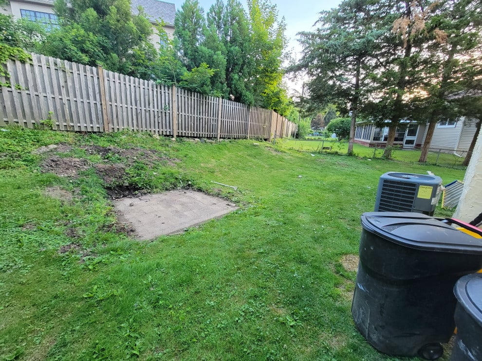 Existing concrete masonry patio previously covered by a shed. The existing hill below the fence. All ideas and suggestions are welcomed.