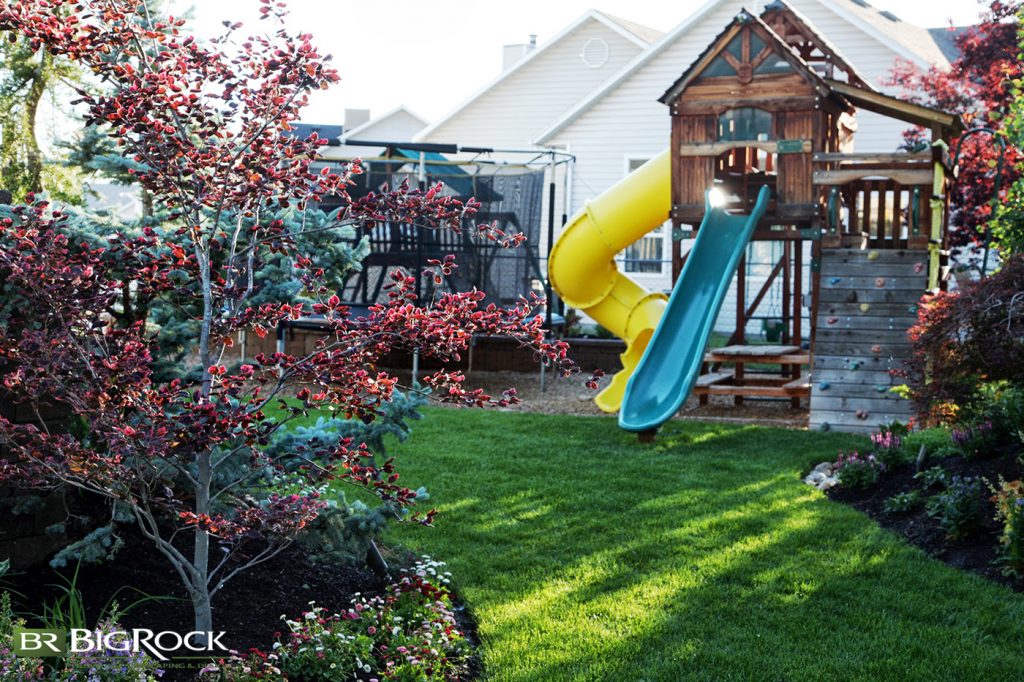 A yellow twisty slide has never looked as good as it has in this backyard. This playhouse and trampoline would normally be an eyesore, but set in the midst of a well-planned yard, they become barely noticeable