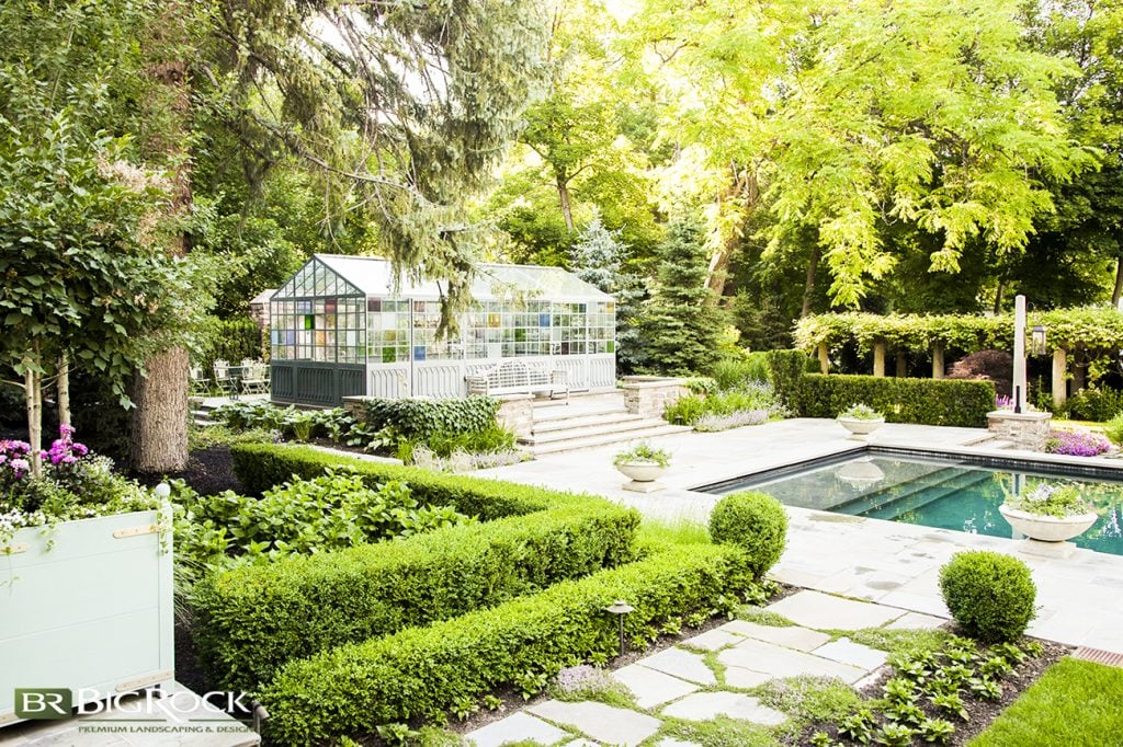 This home has it all: water for tranquility and peace, clipped hedges in layers juxtaposed against climbing vines, flower beds overflowing with plants of all shapes and sizes, and a focal point structure that adds a bit of old-fashioned charm and color to the landscape