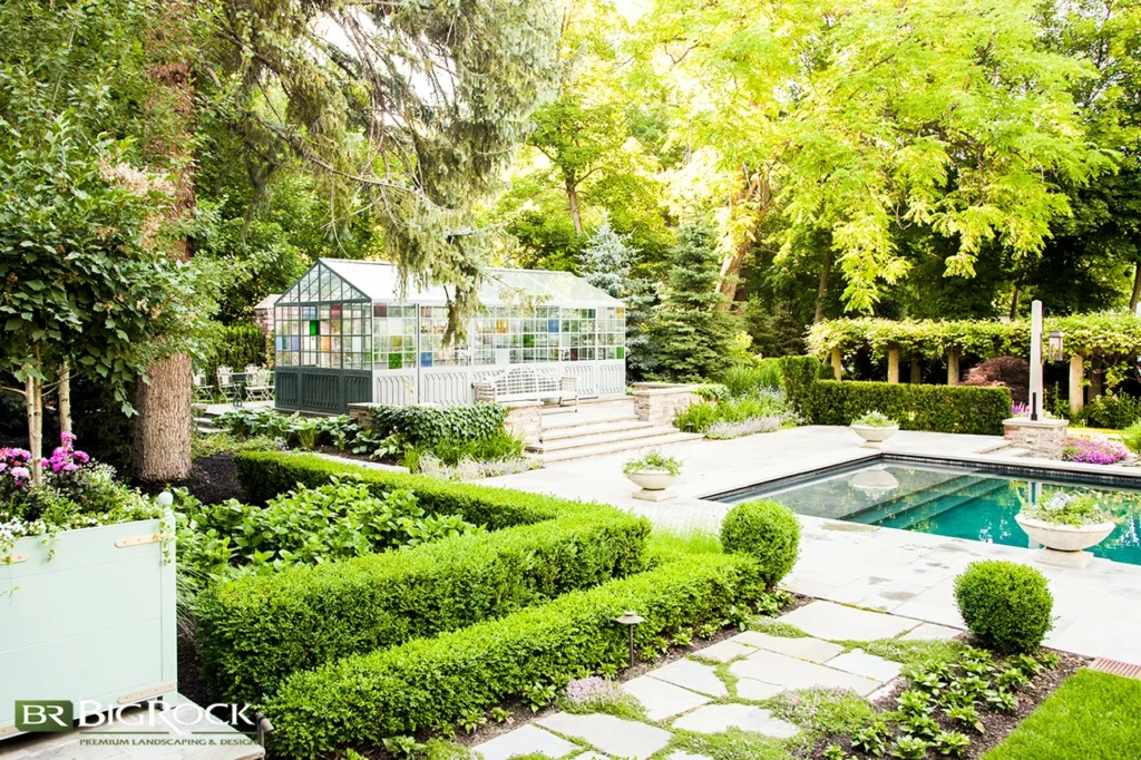 A formal poolside landscape design featuring boxwood hedges shaped for structure and privacy in a refined residential backyard.
